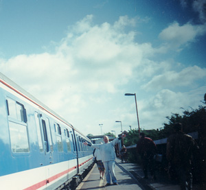 A man on a station platform with arms open wide.
