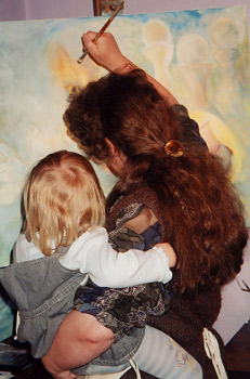 a woman painting with a child on her hip.
